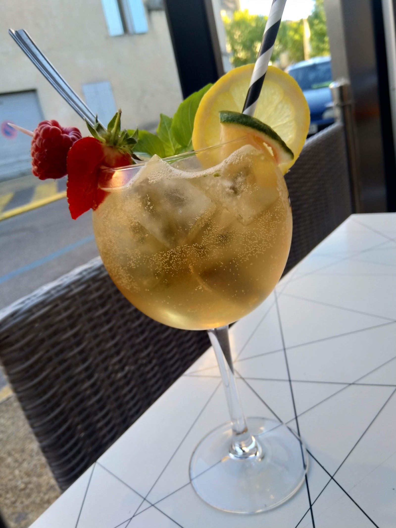 Cocktail frais avec citron, paille et fleur rouge, servi en terrasse