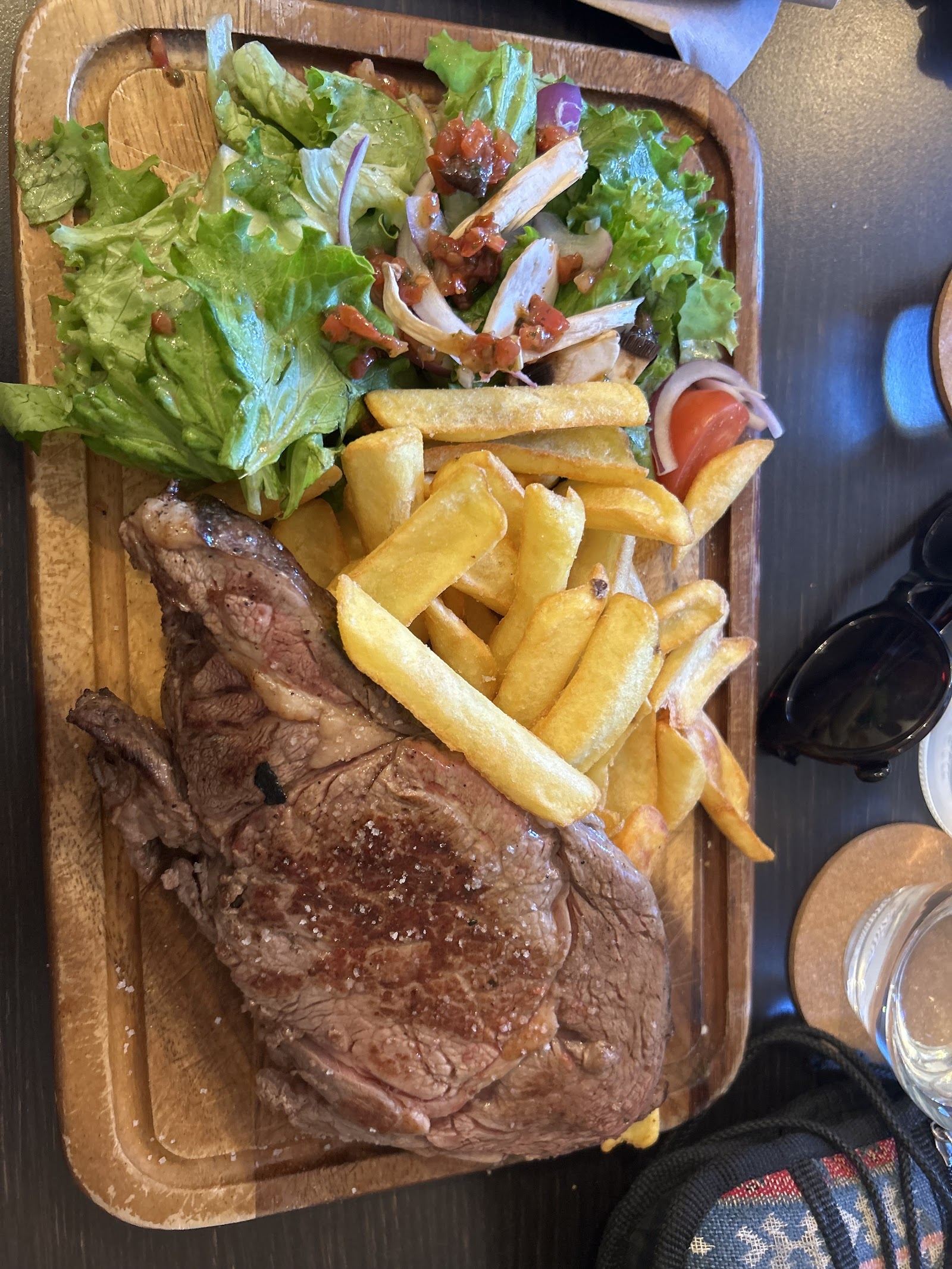 Entrecôte servie sur une planche en bois avec des frites et de la salade