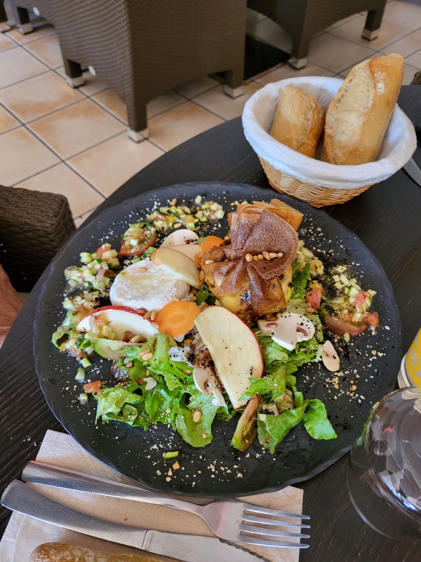 Grande salade composée dans une assiette creuse sombre