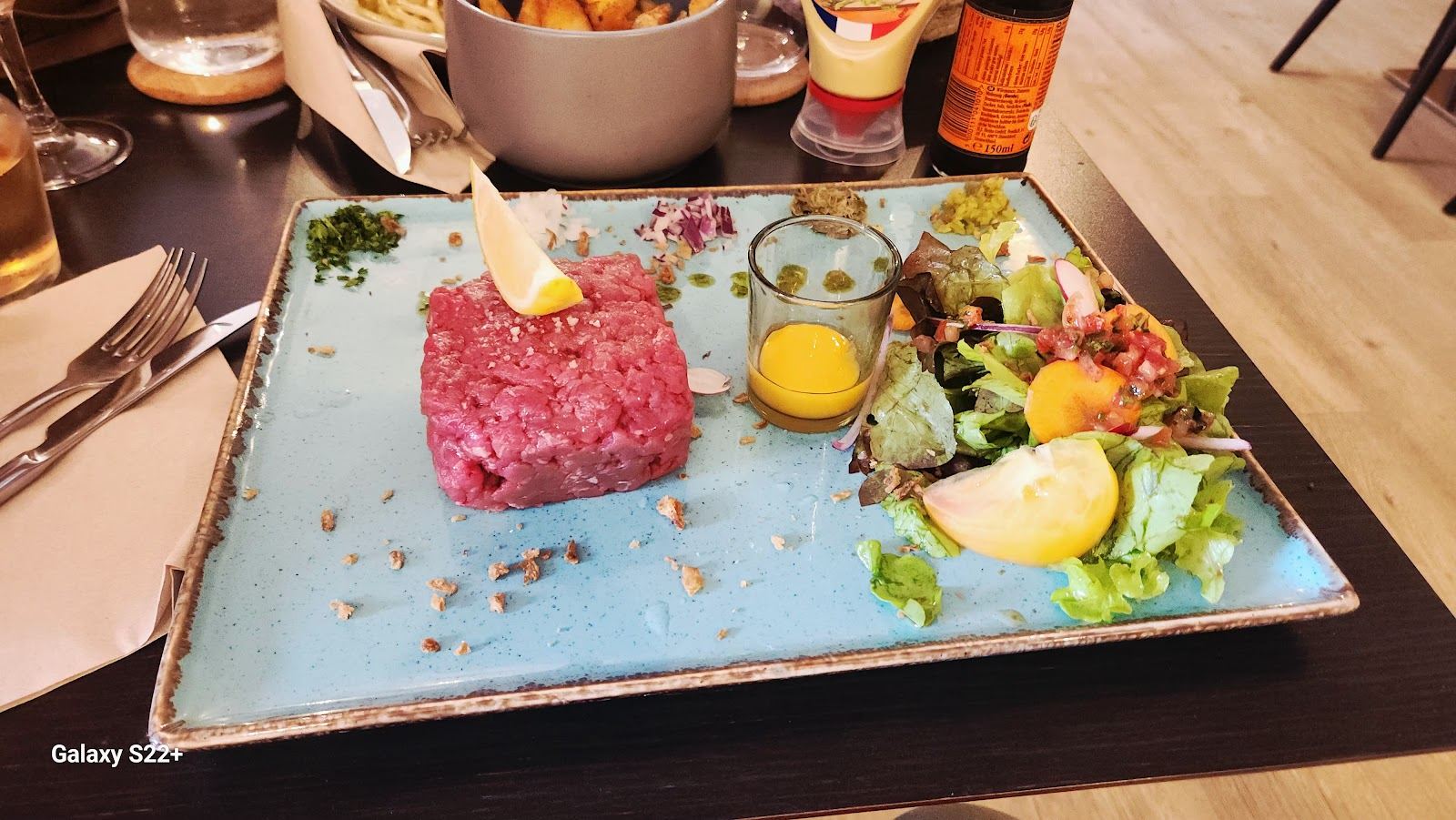 Tartare de bœuf servi avec une salade, un jaune d'œuf et des oignons rouges